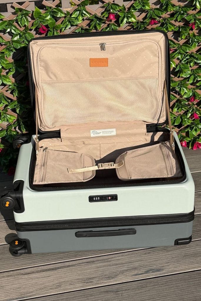 Interior of the LEVEL8 Adventure 24" top loading check-in luggage. Beige recycled fabric looks lux, and compression straps with mesh pockets and big pocket on the top opening flap.